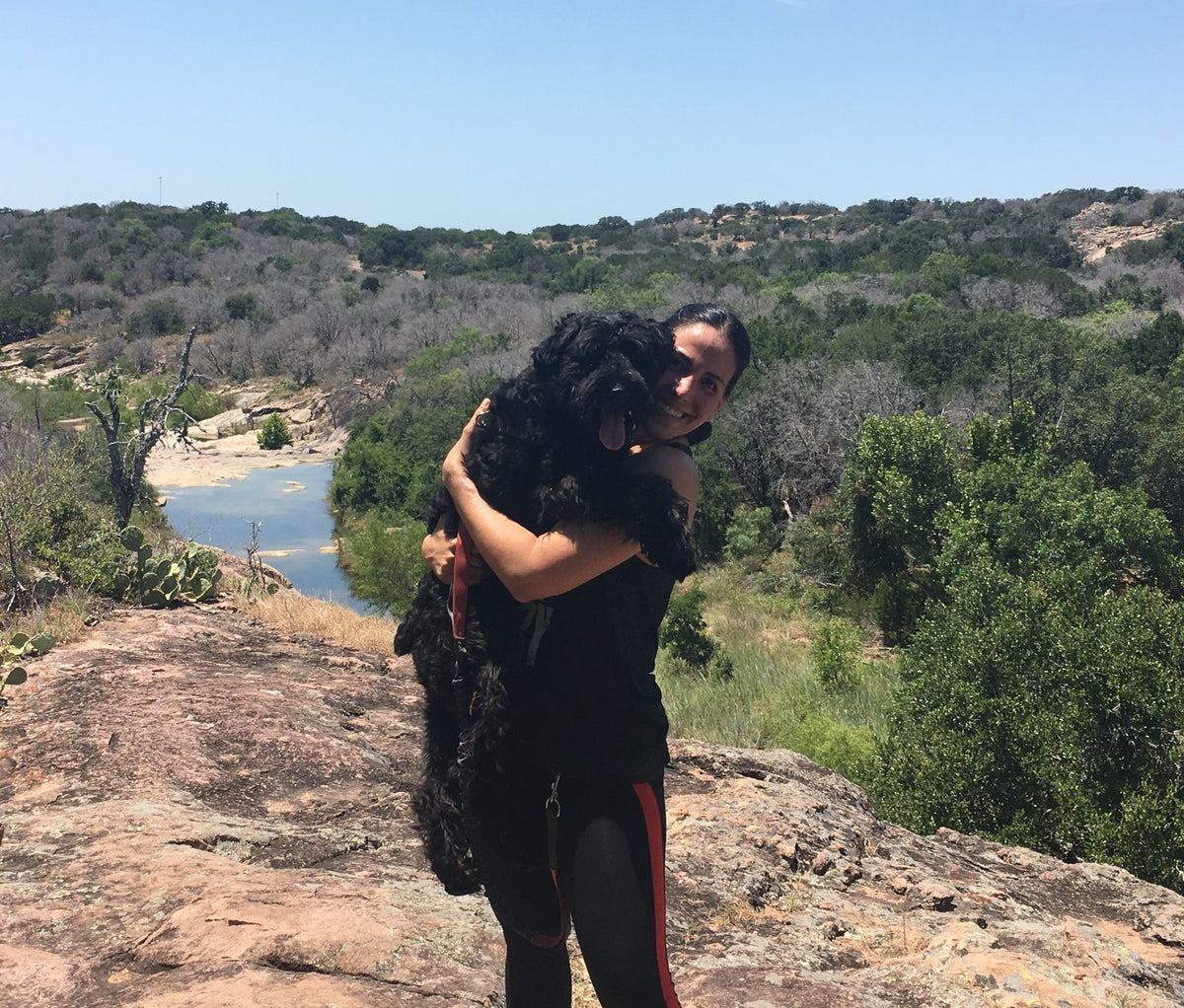 The author hugging Sascha on a rock overlook in the Texas hill country