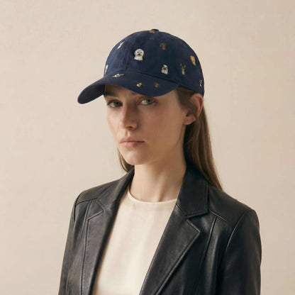Woman wearing a navy cap with embroidered designs on a beige background