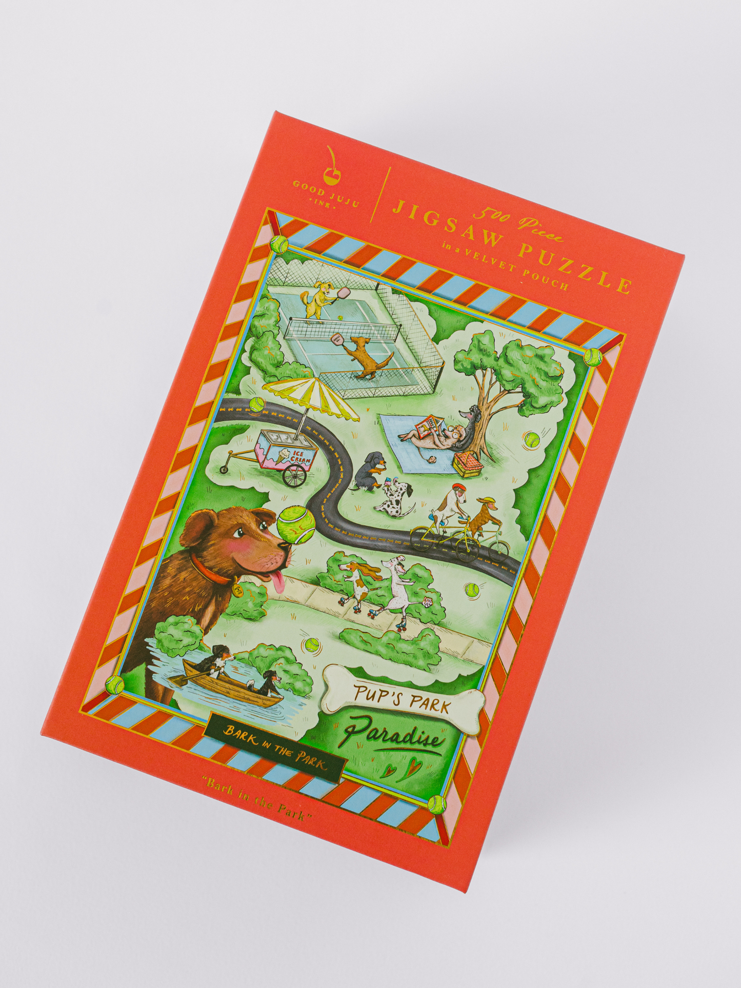 Bark in the Park 500-piece dog jigsaw puzzle with playful pups and gold foil accents in a magnetic keepsake box