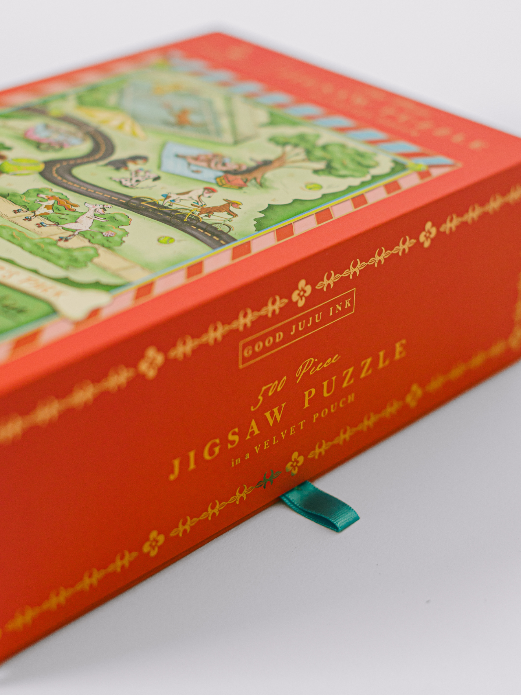 Bark in the Park 500-piece dog jigsaw puzzle with playful pups and gold foil accents in a magnetic keepsake box