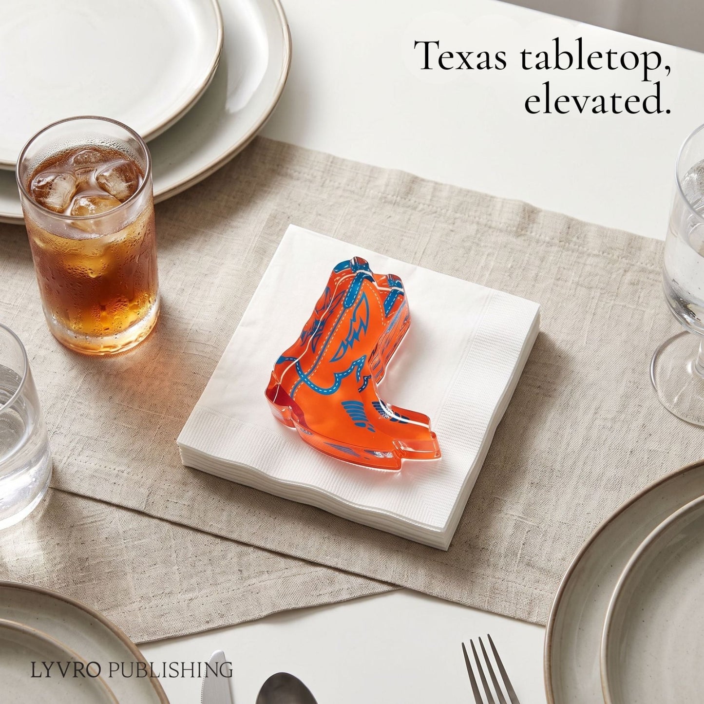 An orange and blue patterned boot-shaped acrylic napkin holder sits on a white napkin stack on a beige table runner, styled on a dining table with plates, a glass of iced tea, and water glasses. Text in the top right reads 'Texas tabletop, elevated.
