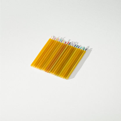 Set of 20 beeswax candles with colorful tips on a light background.