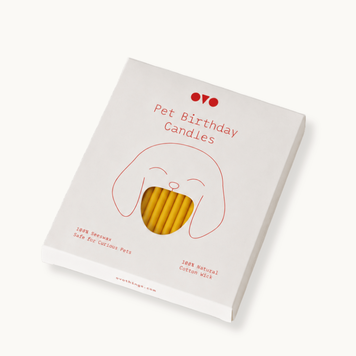 A boxed candle product labeled 'Pet Birthday Candles' shown at an angle on a clean white background. The package is white with a simple red line drawing of a dog face and red text, with a clear window revealing beeswax candles inside.