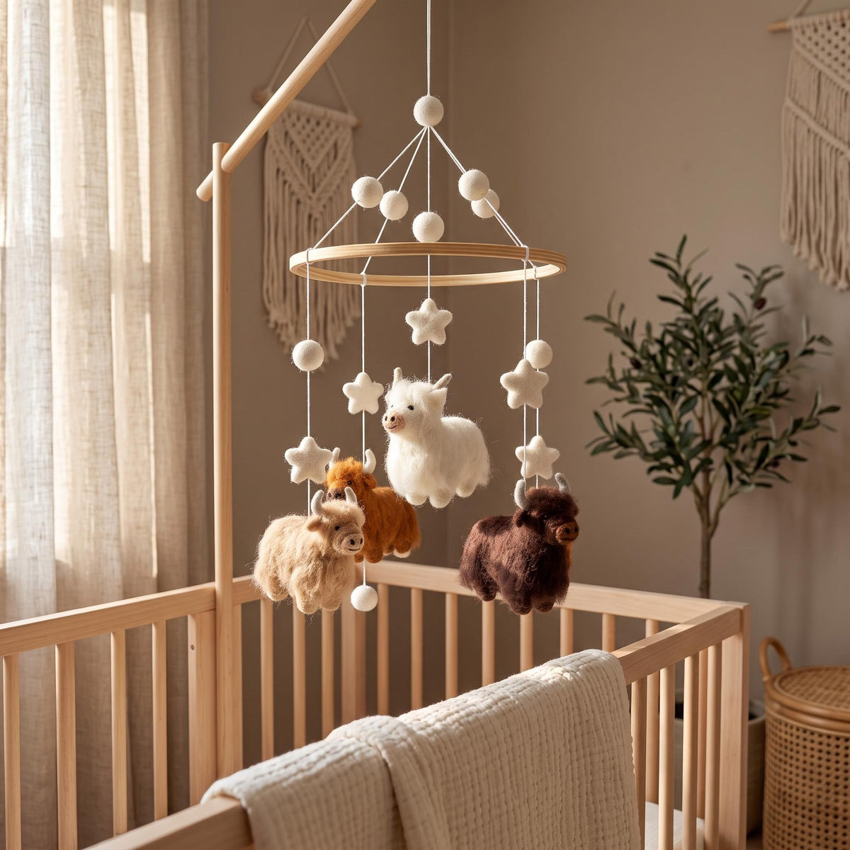Handcrafted Highland cow felt baby mobile featuring fluffy cows in cream, caramel, and chocolate brown, with felt stars and wooden hoop, hanging above a natural wood crib in a neutral nursery.
