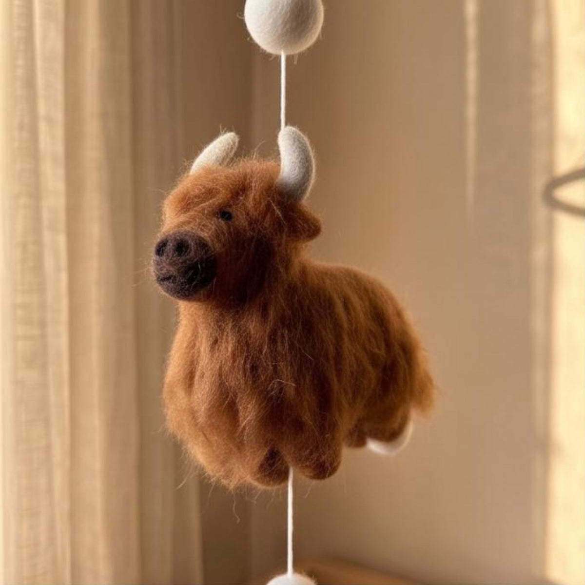 Handcrafted Highland cow felt baby mobile featuring fluffy cow in brown.