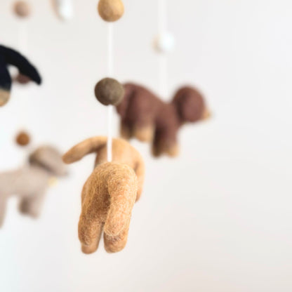 A close-up of a felt Dachshund dog baby mobile against a plain light background.