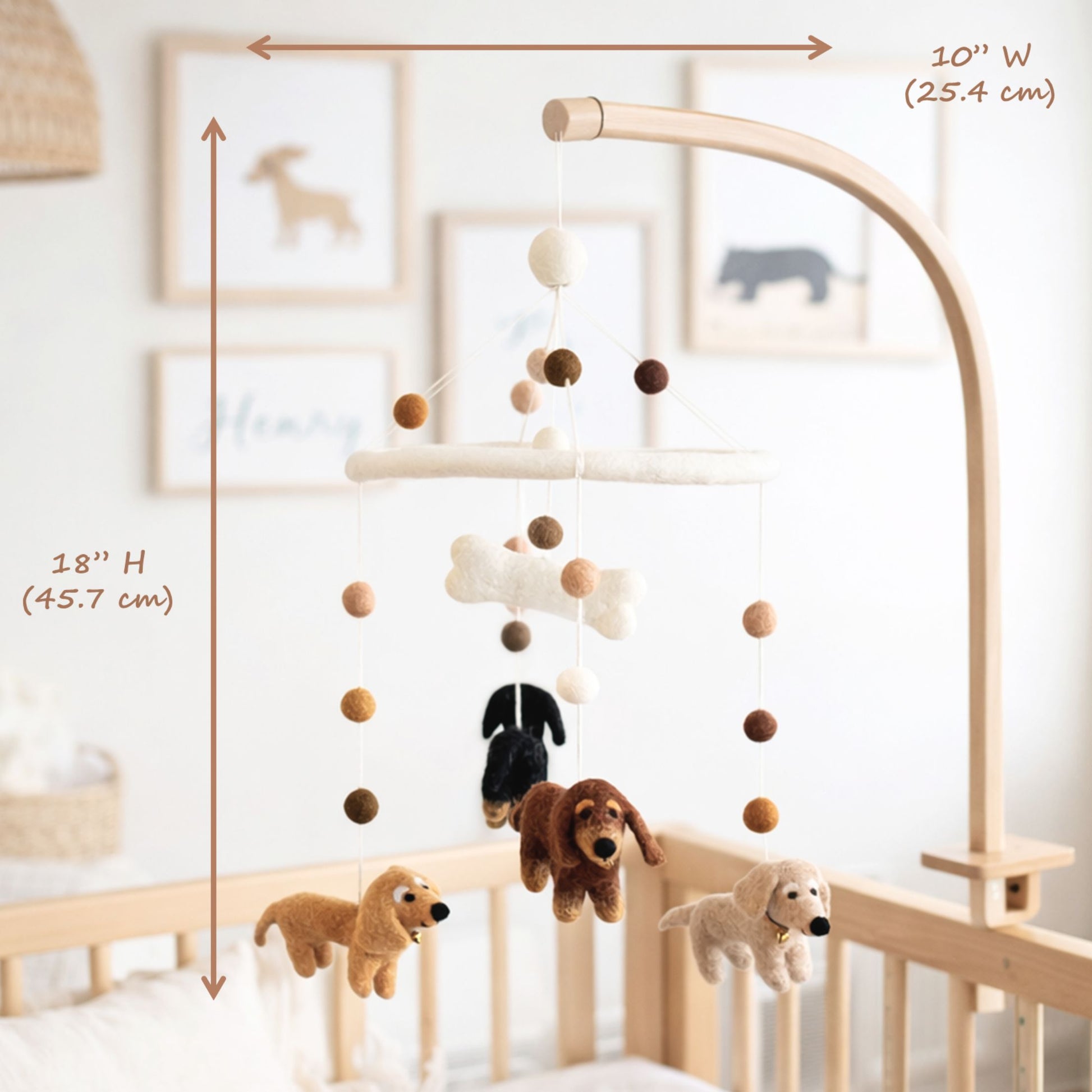 A wooden baby crib with a hanging mobile featuring Dachshund felt dogs, circles, and a bone-shaped ornament. The image includes dimension annotations showing the mobile's height and width.