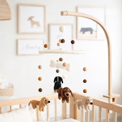 Handcrafted felt baby mobile featuring four Dachshund dogs, a felt bone, and coordinating neutral-toned felt balls hanging over a wooden crib.