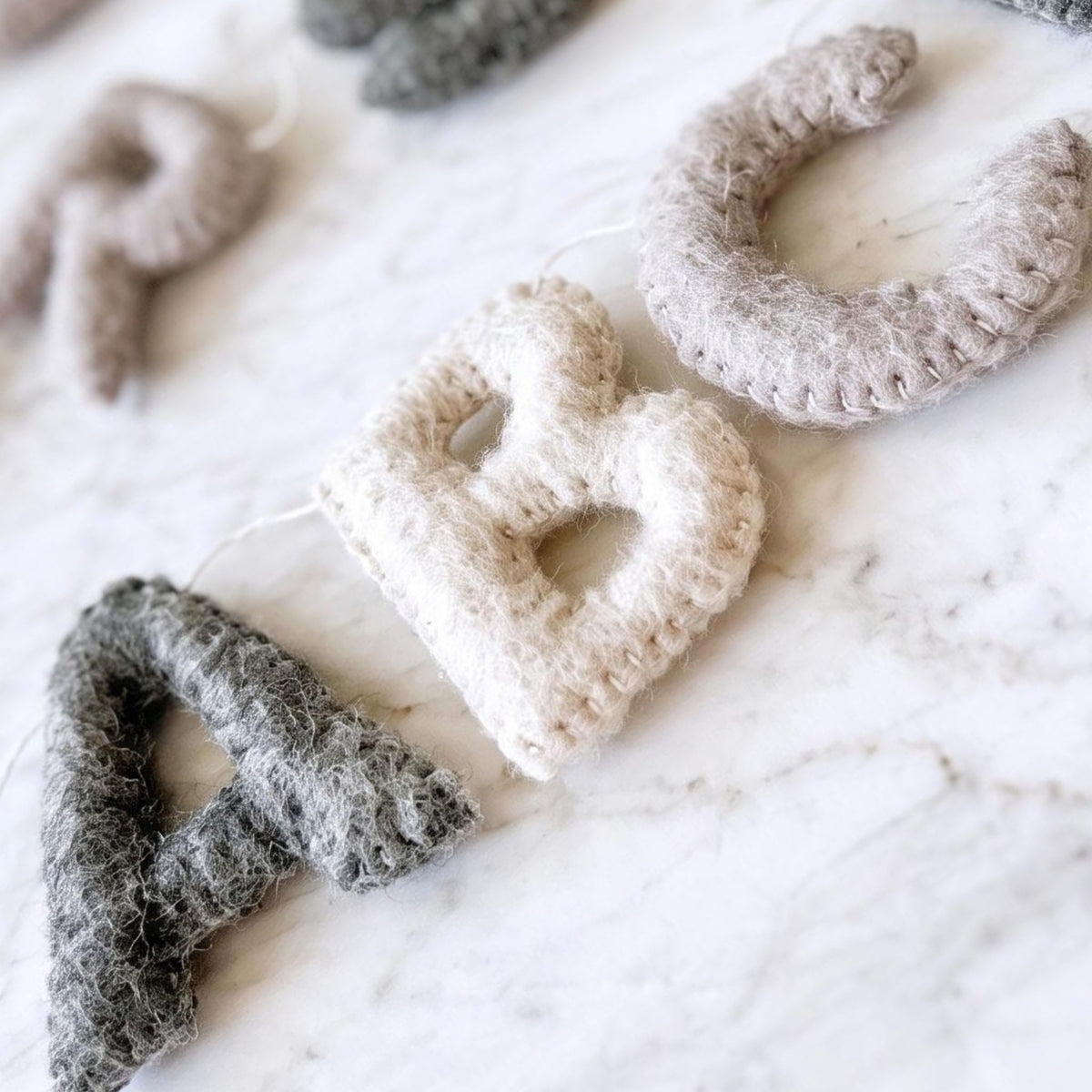 Grey-toned felt alphabet garland showing letters A, B, and C.
