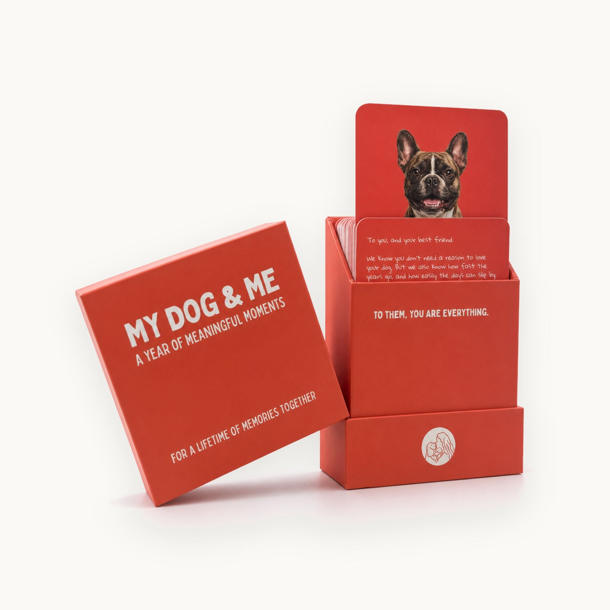 A red activity card set for engaging with pets, showing the outer box labeled 'MY DOG & ME' next to a display stand holding printed cards with a dog photo and memorial messages, on a clean white background.