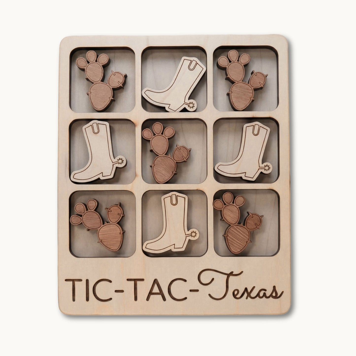 A wooden 3x3 tic-tac game board engraved with 'TIC-TAC-Texas' at the bottom, featuring laser-cut cactus and cowboy boot shapes in two natural wood tones.