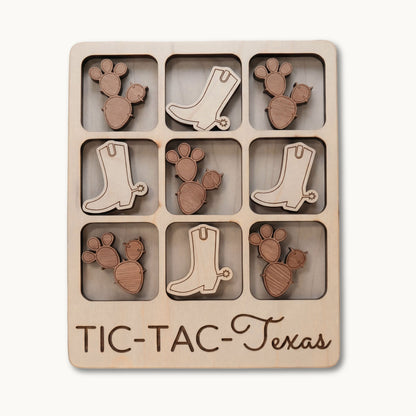A wooden 3x3 tic-tac game board engraved with 'TIC-TAC-Texas' at the bottom, featuring laser-cut cactus and cowboy boot shapes in two natural wood tones.